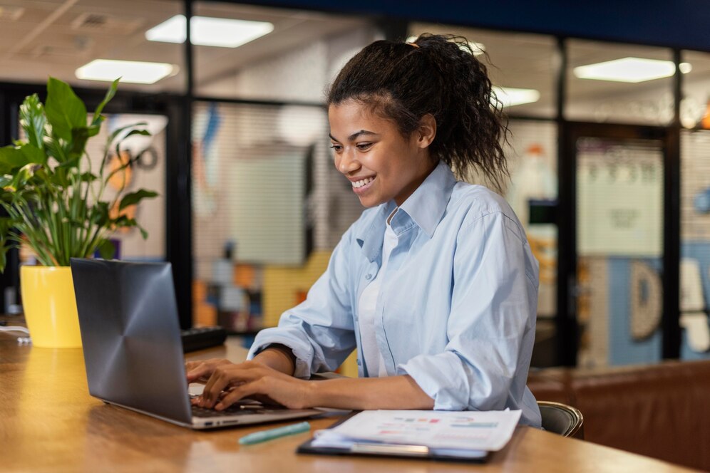 vista lateral de uma mulher sorridente trabalhando com um laptop no escritorio 23 2148908808